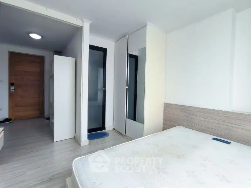 Bright bedroom with modern wardrobe and wooden door, perfect for cozy living.