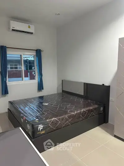 Modern bedroom with sleek design and natural light, featuring a comfortable bed and air conditioning.