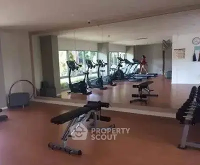 Spacious gym with modern equipment and mirrored walls in luxury real estate property.