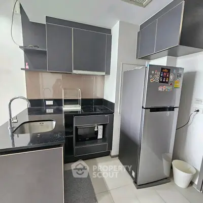 Modern kitchen with sleek cabinets and stainless steel fridge in a stylish apartment.
