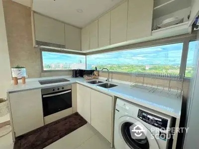 Modern kitchen with stunning view, featuring built-in oven and washing machine.