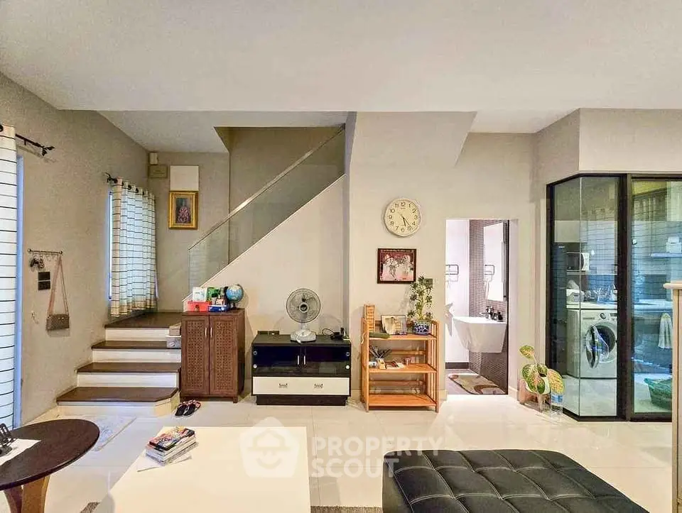 Spacious modern living room with staircase and glass partition, ideal for family gatherings.