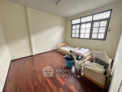 Spacious bedroom with wooden flooring and large window, perfect for natural light.