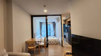 Modern apartment interior with open living and dining area, featuring a cozy bedroom and sleek kitchen appliances.