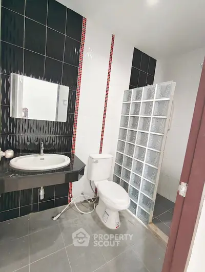 Modern bathroom with sleek black and white tiles and glass block shower.
