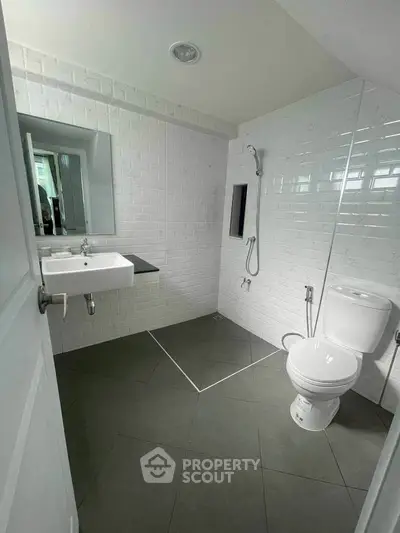 Modern minimalist bathroom with sleek white tiles and contemporary fixtures.