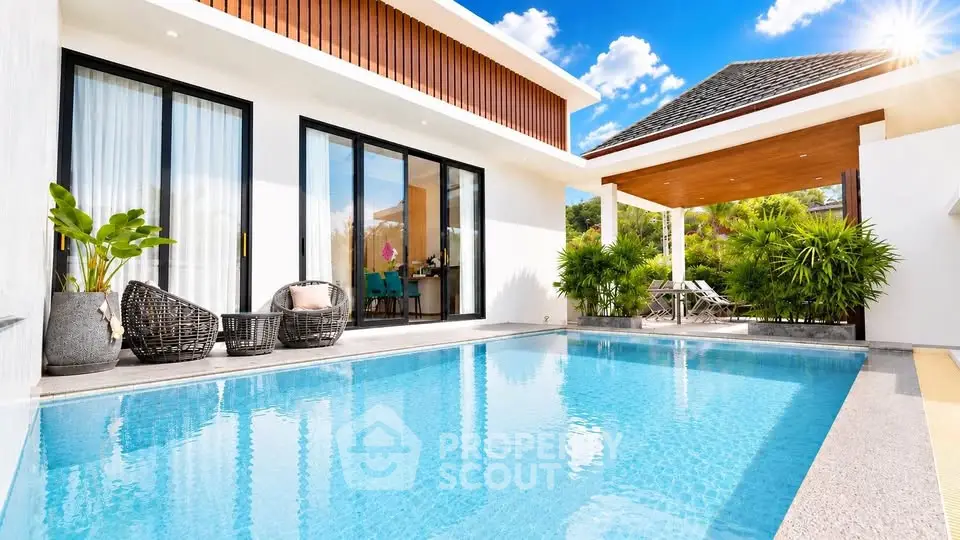 Luxurious villa with private pool and modern outdoor seating area under sunny skies.