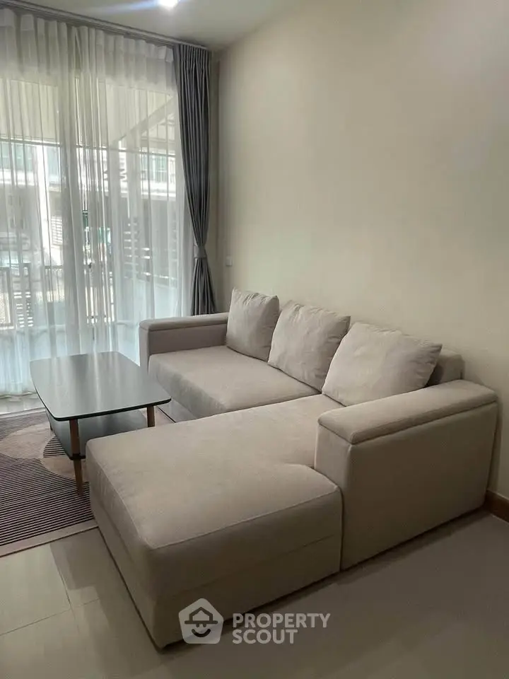 Modern living room with cozy beige sectional sofa and glass coffee table, perfect for relaxation.