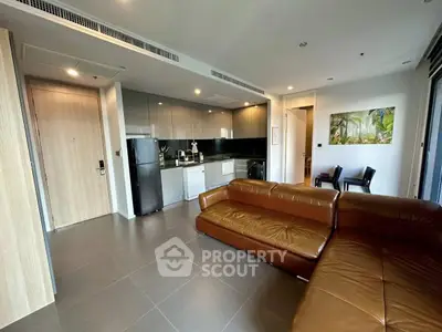 Modern living room with sleek kitchen and leather sofa in open layout apartment.