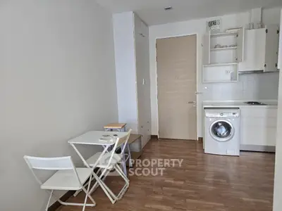 Cozy apartment interior with compact kitchen and dining area featuring washing machine and minimalist furniture.