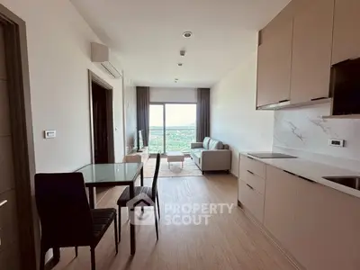 Modern open-plan living room with kitchen, featuring sleek cabinetry and a scenic view from the balcony.