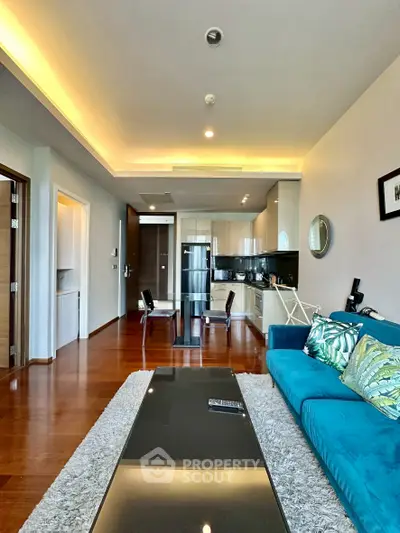 Modern living room with open kitchen, stylish decor, and wooden flooring in a contemporary apartment.