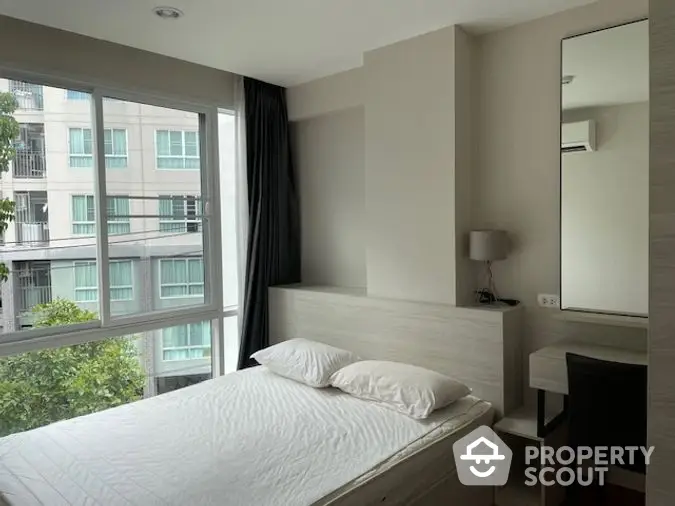 Modern minimalist bedroom with large window offering ample natural light and a serene city view, perfect for urban living.