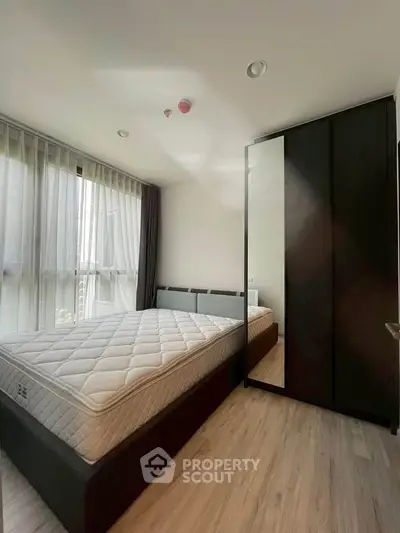 Modern bedroom with large window and sleek wardrobe in a stylish apartment.