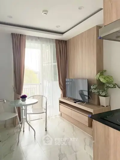 Modern living room with natural light, TV, and cozy seating area in stylish apartment.