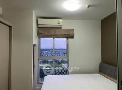 Cozy bedroom with large window offering stunning cityscape views, perfect for relaxation and comfort.