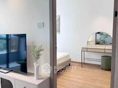 Modern bedroom with stylish vanity and TV, featuring elegant decor and natural light.