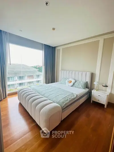 Spacious bedroom with large window and modern decor in a stylish apartment.