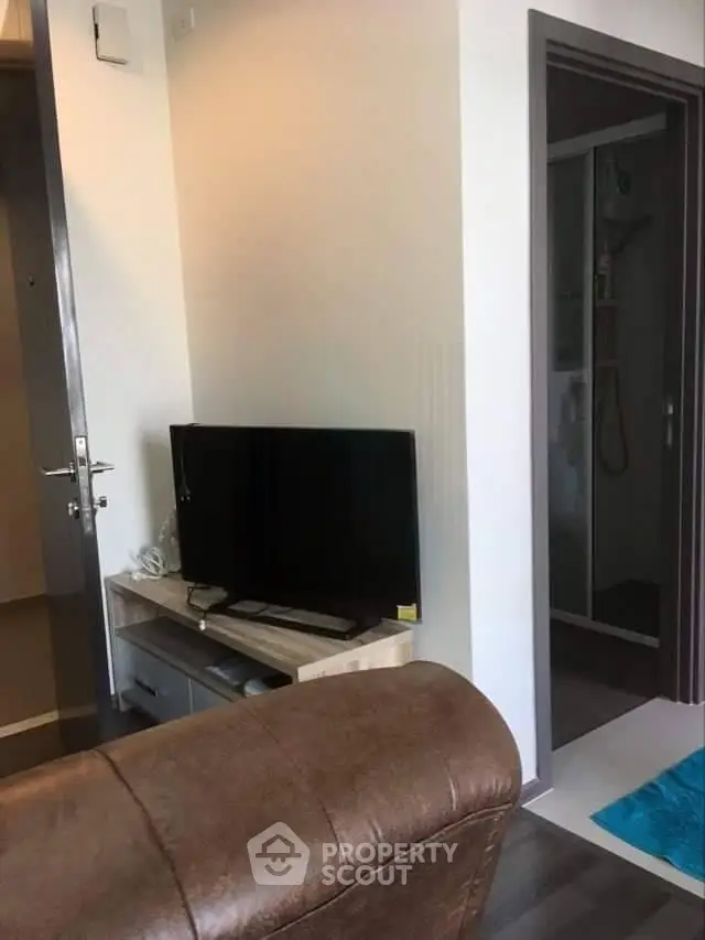 Cozy living room with modern TV setup and adjacent bathroom entrance.