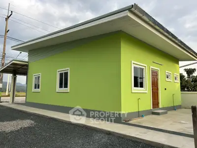 Modern green single-story house with minimalist design and spacious surroundings.