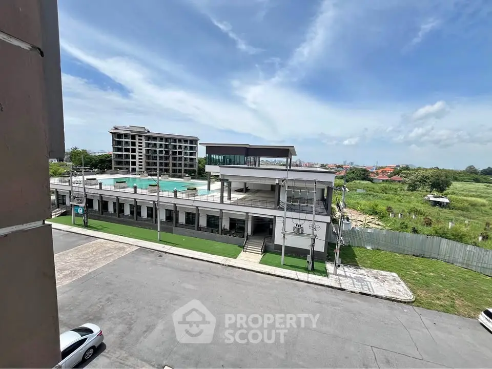 Modern commercial building with rooftop pool and spacious parking area