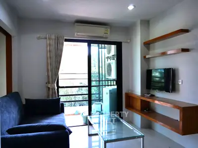 Modern living room with balcony, featuring sleek furniture and natural light.