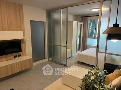 Modern studio apartment with sliding glass doors separating bedroom and living area, featuring stylish decor.