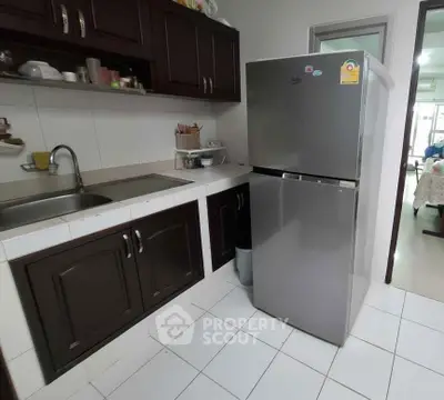 Cozy kitchen with modern fridge and dark wood cabinets, perfect for culinary enthusiasts.
