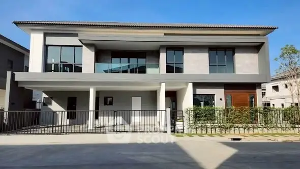 Modern two-story house with large windows and sleek design in a suburban neighborhood.