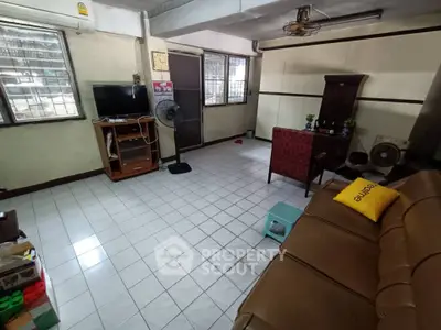 Spacious living room with tiled floor, cozy seating, and natural light from large windows.