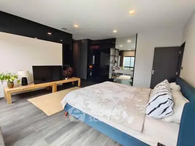 Spacious modern bedroom with stylish decor and large TV, perfect for relaxation.