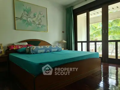 Spacious bedroom with large windows and tropical view, featuring elegant wooden flooring and modern decor.