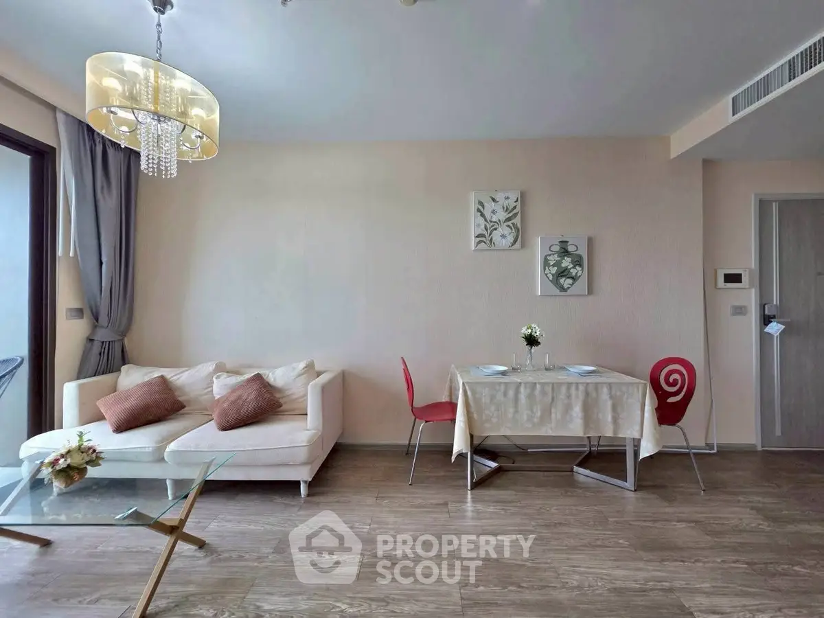 Modern living room with elegant decor and dining area, featuring a cozy sofa and stylish chandelier.