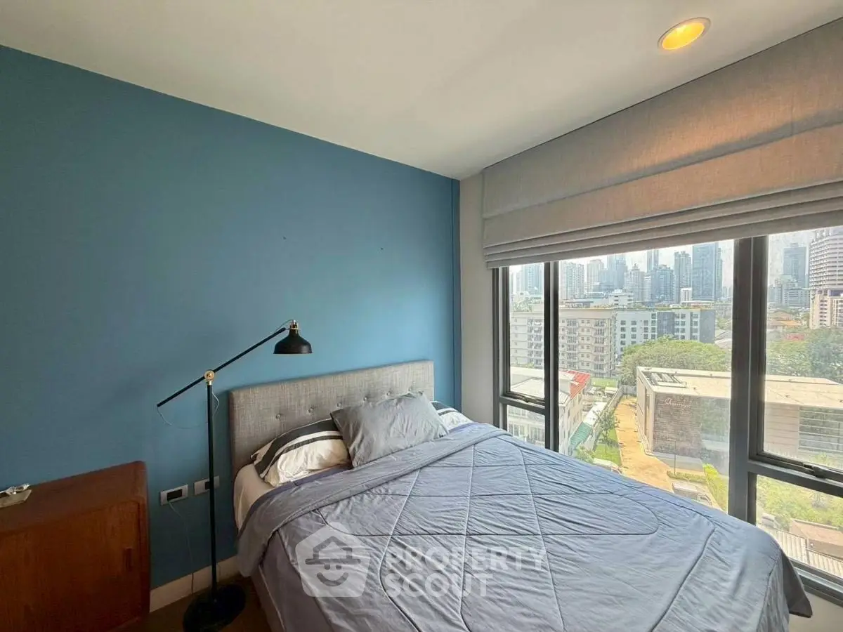 Modern bedroom with city view, featuring a cozy bed and stylish decor in a high-rise apartment.
