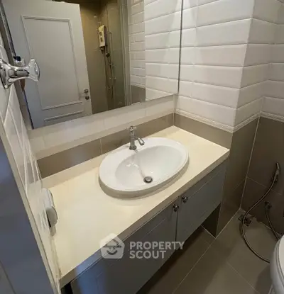 Modern bathroom with sleek sink and tiled walls, showcasing contemporary design and functionality.
