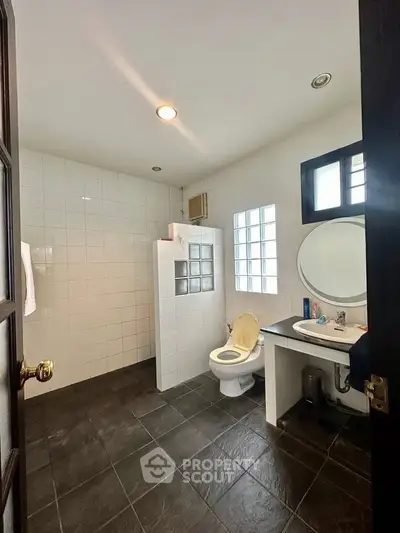Spacious modern bathroom with tiled floors and glass block partition