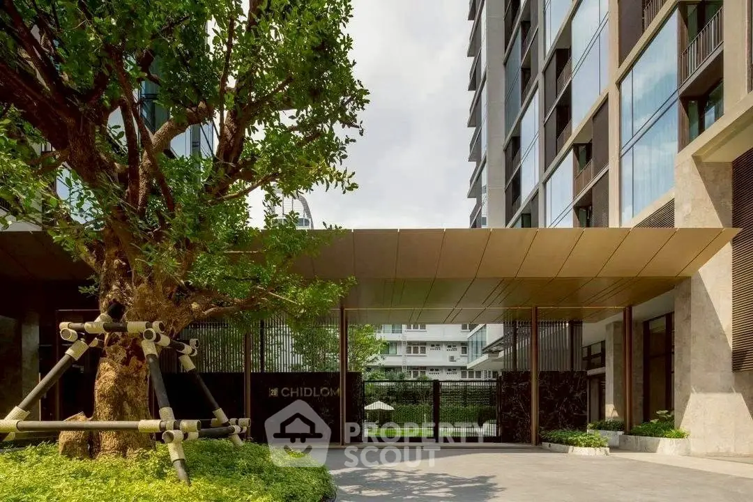 Modern building entrance with lush greenery and sleek architectural design.