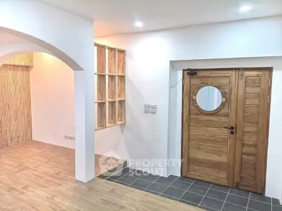 Modern interior with wooden door and stylish archway, featuring elegant wood flooring and recessed lighting.