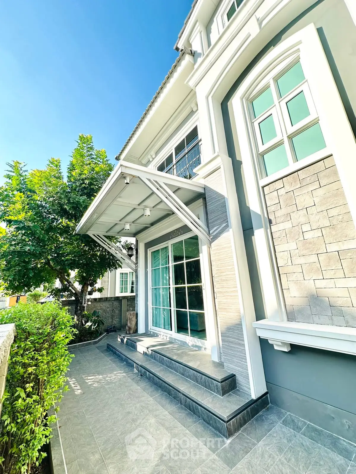 Charming modern house exterior with elegant stone facade and lush greenery