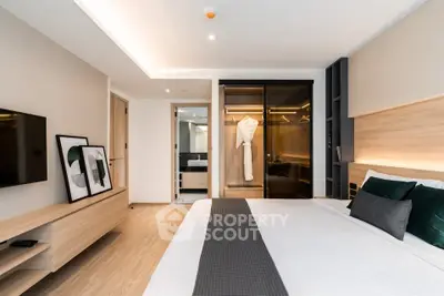 Modern bedroom with sleek design, featuring a large bed, wall-mounted TV, and stylish decor.