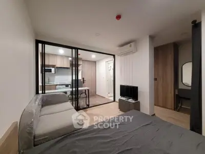 Modern studio apartment with open kitchen and cozy living area, featuring sleek furniture and contemporary design.