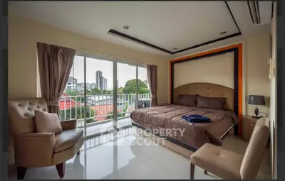 Spacious bedroom with large windows and city view, featuring elegant furnishings and natural light.