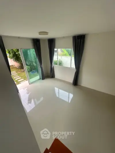 Spacious unfurnished living room with large windows and garden view