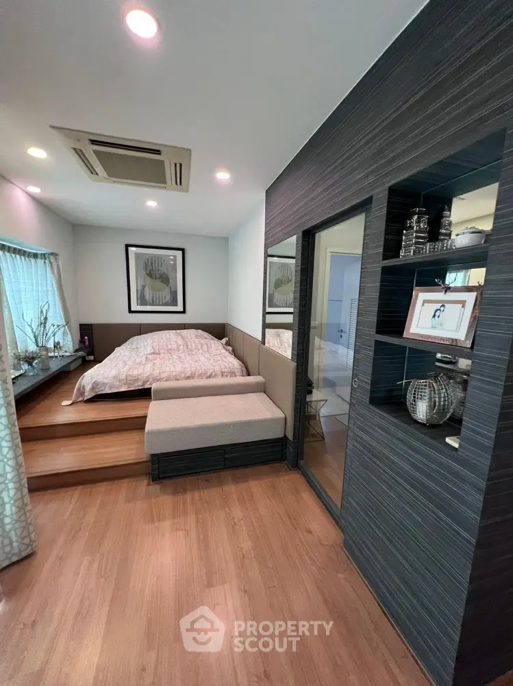 Modern bedroom with stylish decor and wooden flooring, featuring a cozy bed and elegant shelving.
