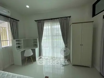 Bright bedroom with study area, wardrobe, and large window with curtains.