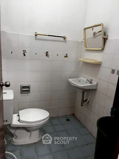 Compact bathroom with white tiles and basic fixtures, ideal for small spaces.