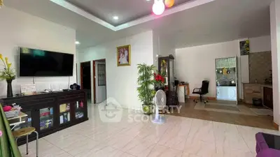 Spacious living room with modern decor and open layout, featuring a large TV and elegant furnishings.