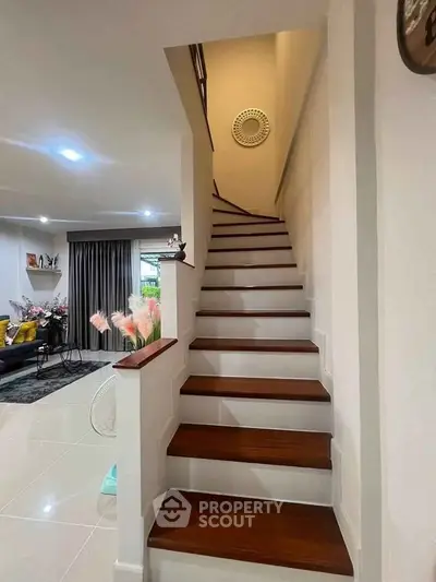 Elegant staircase leading to upper floor with cozy living room view, perfect for modern family living.