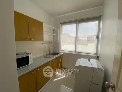 Compact kitchen with natural light, featuring wooden cabinets and modern appliances.