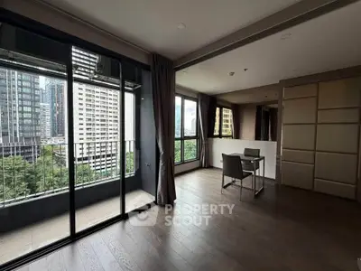 Spacious modern living room with large windows and city view, featuring sleek wooden flooring and minimalist decor.